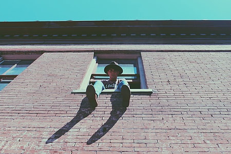 man sitting on window during daytime thumbnail