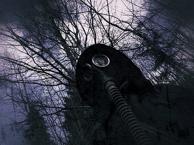 person in black hooded coat with black gas mask in forest thumbnail