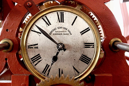round gold-colored analog clock on red steel frame thumbnail
