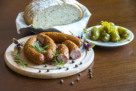 cooked sausages on plate. near pickled cucumber on plate and bread on basket thumbnail