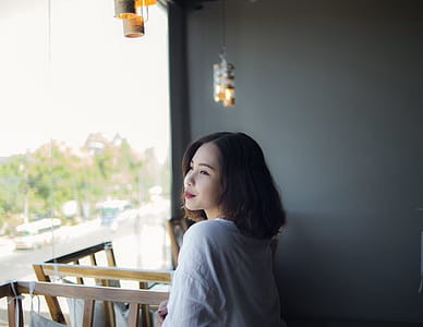 Woman in White Top Looking Outside Window thumbnail