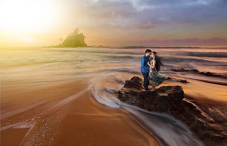 time lapse photography of couple standing on the rock beside beach shore line thumbnail
