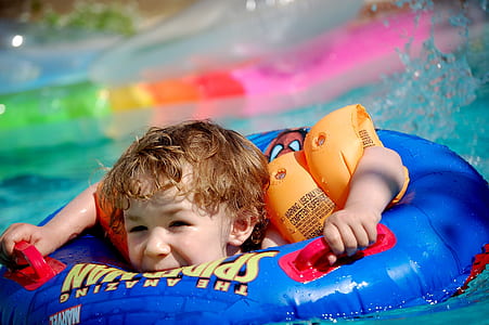toddler wearing blue inflatable float on swimming pool thumbnail
