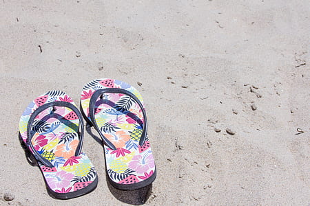 pair of pink flip-flops on top of sand thumbnail