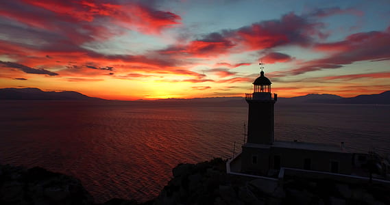 lighthouse near body of water during golden hour thumbnail