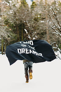 person carrying Land of the Dreamer-printed banner on snowfield thumbnail