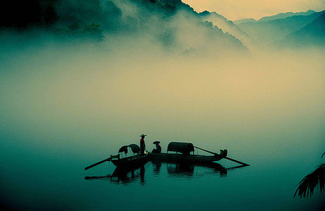 silhouette of people on wooden paddle boats on foggy lake thumbnail