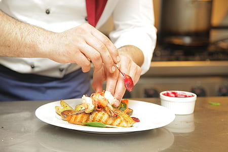 chef arranging food dish on white ceramic plate thumbnail