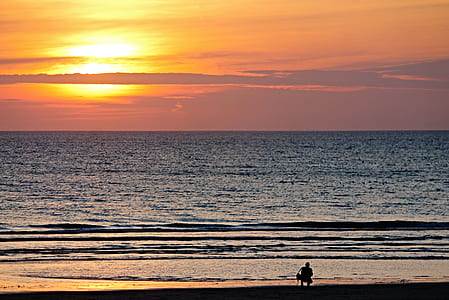person on seashore near body of water during golden house thumbnail