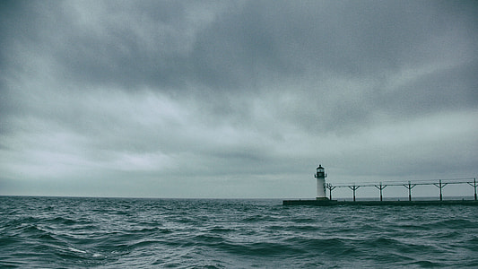 white lighthouse between calm body of water thumbnail