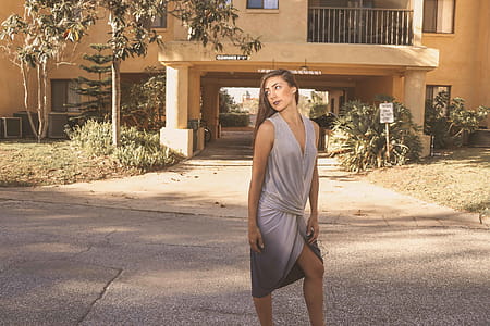 Woman in Gray Deep V-neck Sleeveless Tulip Dress Standing on Gray Floor thumbnail