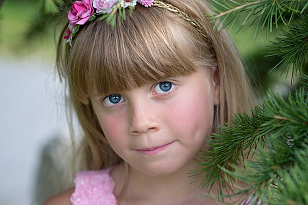 girl standing beside green Christmas tree thumbnail