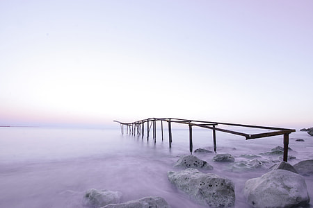 black wooden dock near rocks and body of water during daytime thumbnail