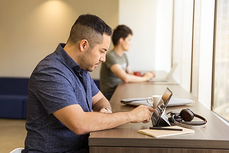man in blue button-down shirt using tablet computer thumbnail