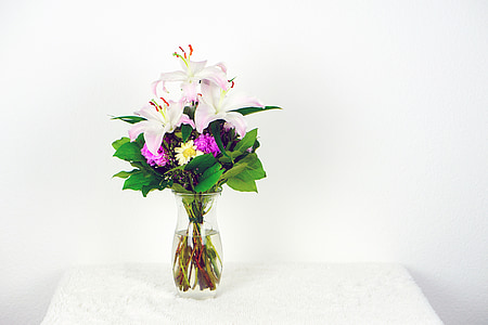 white and pink lily flowers in clear glass vase on table thumbnail