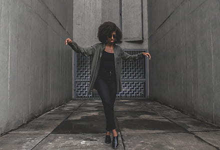 woman wearing gray jacket standing between buildings thumbnail