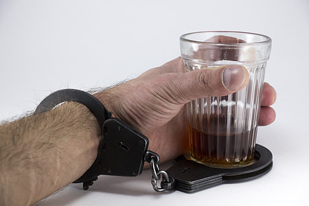 person wearing black handcuff and holding clear glass cup thumbnail