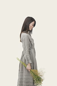 woman wearing gray long-sleeved dress holding flower thumbnail