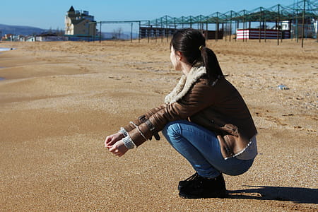 Woman Crouching on Brown Sand thumbnail