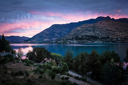 body of water near rocky mountain under blue and pink sky thumbnail