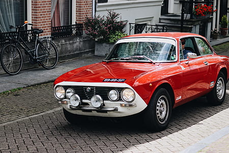 red coupe on brown pavement thumbnail