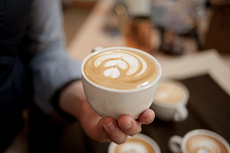 person holding cappuccino-filled teacup thumbnail