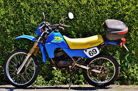 blue dirtbike in front of bushes thumbnail