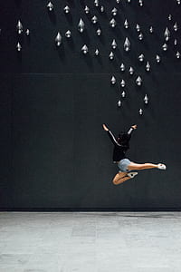 minimalist photography of jumping woman near wall with water droplet accents thumbnail