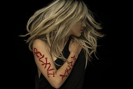 woman wearing black one shoulder top with tattoo on her arm thumbnail
