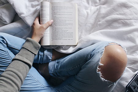 person holding book on white textile thumbnail