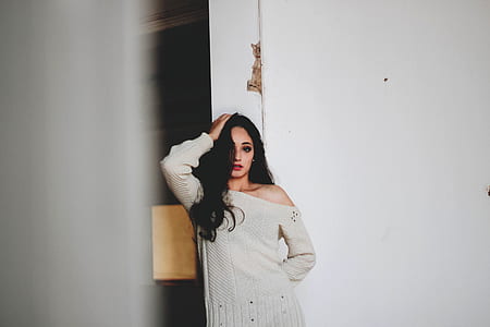 woman wearing gray dress leaning on white wall thumbnail