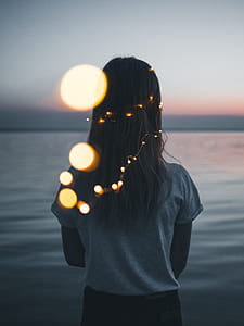 woman standing on shore with lighted headdress thumbnail