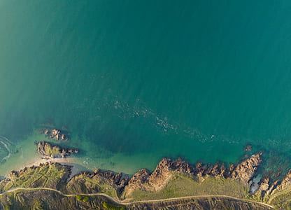 aerial photography of sea and mountain with road track thumbnail