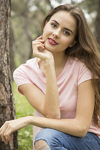 woman wearing pink shirt and blue denim bottoms sitting beside tree thumbnail