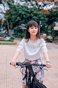 Woman Wearing White Blouse and Multicolored Floral Skirt Riding Bike thumbnail