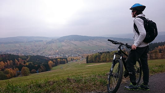 man holding mountain bike facing mountain hill thumbnail