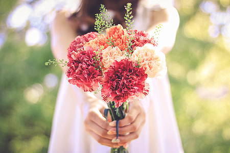selective focus photography of woman holding bouquet of flowers thumbnail