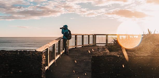 person standing beside fence while taking a photo thumbnail