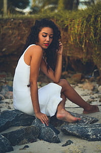 woman wearing white sleeveless mini dress sitting on rock thumbnail