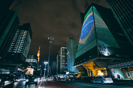 Cars Traveling on Road Between Buildings during Nighttime thumbnail