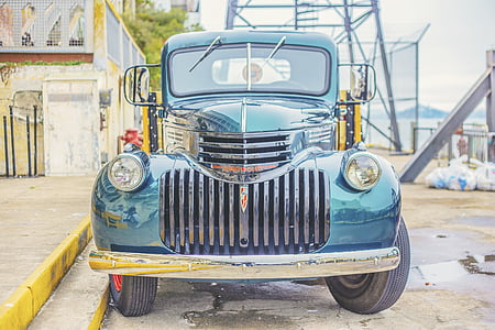 blue classic vehicle park on roadside near gray building thumbnail