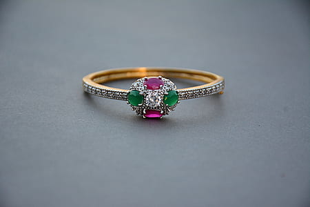 gold-colored assorted-color gemstone encrusted ring on beige surface thumbnail