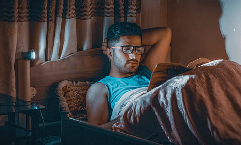 man reading book lying on bed thumbnail