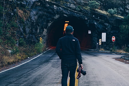 man holding DSLR camera near tunnel road thumbnail