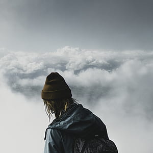 person wearing brown knitted cap surrounded by clouds thumbnail
