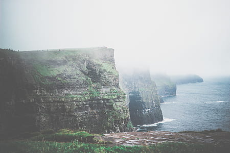 rock formation near body of water during foggy day thumbnail