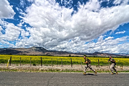 two soldiers running beside grass field and mountain range at daytime thumbnail
