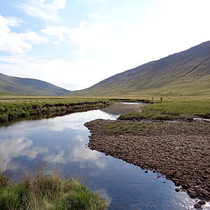 photo of mountain near body of water under white and blue sky at daytime thumbnail