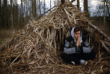 man wearing gray and black hoodie sitting while praying thumbnail