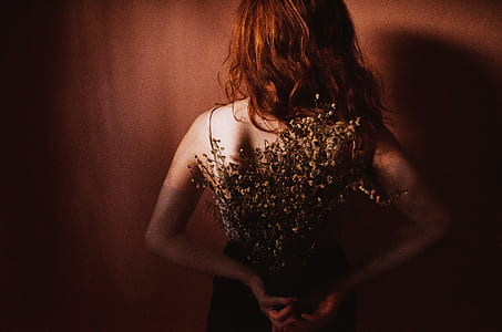 woman showing her back while holding flower thumbnail